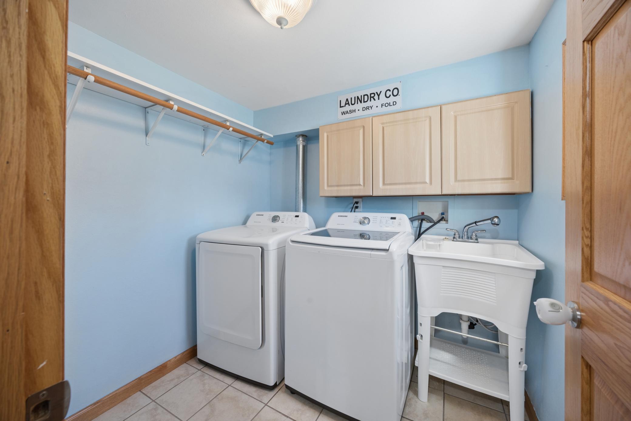 Main floor laundry complete with laundry sink, cupboard storage, and a hanging bar!