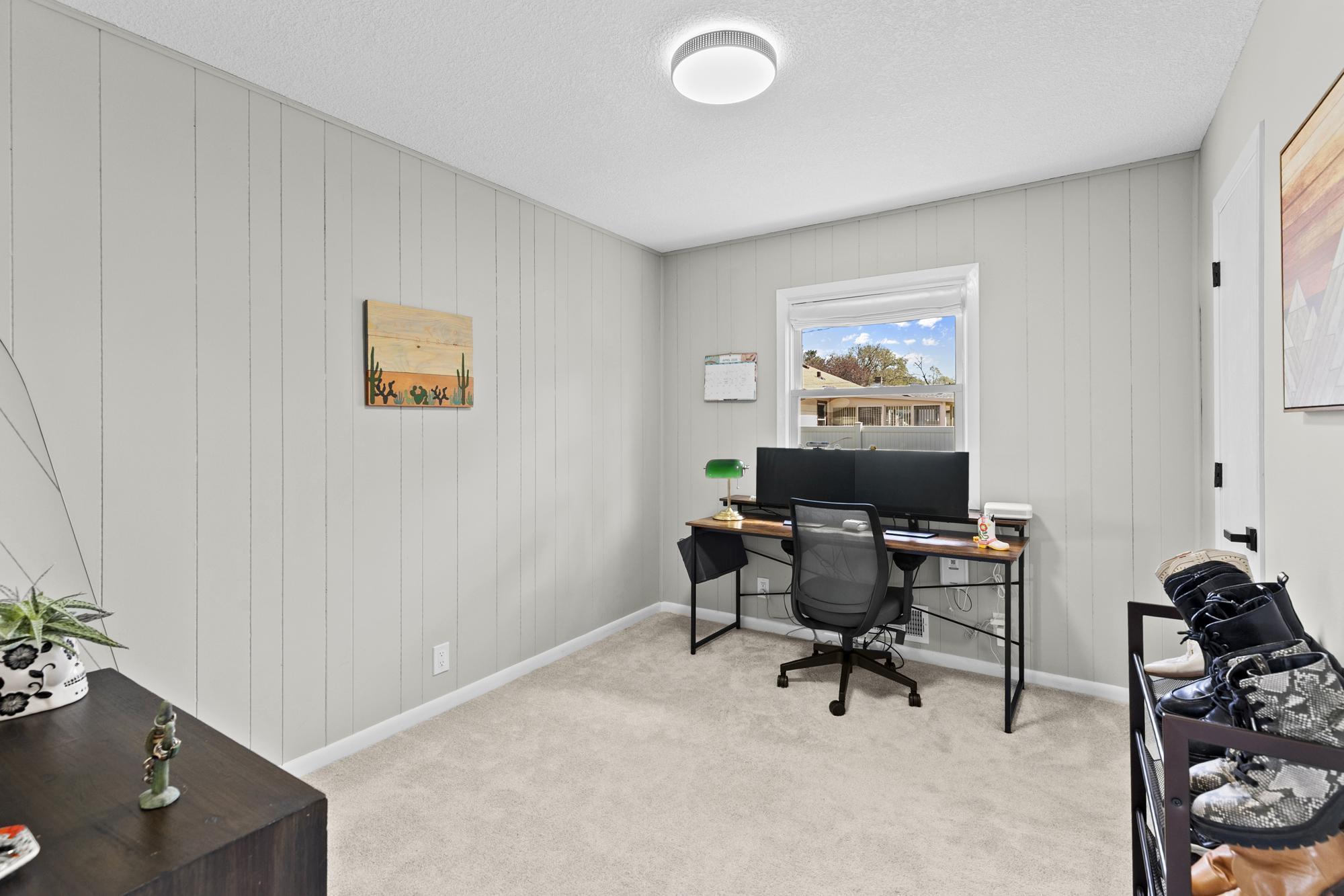 This versatile main-floor bedroom makes an excellent dedicated home office, featuring crisp white trim, a ceiling fan, and great natural light.