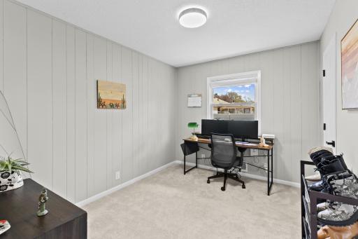 This versatile main-floor bedroom makes an excellent dedicated home office, featuring crisp white trim, a ceiling fan, and great natural light.