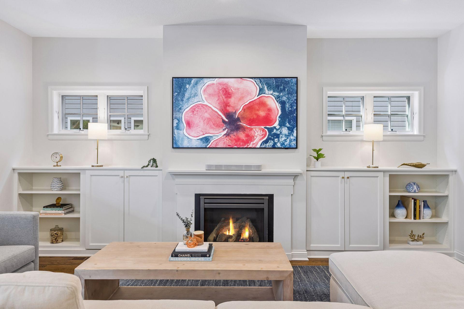 Gas fireplace surrounded by custom built-ins, and windows for natural light.