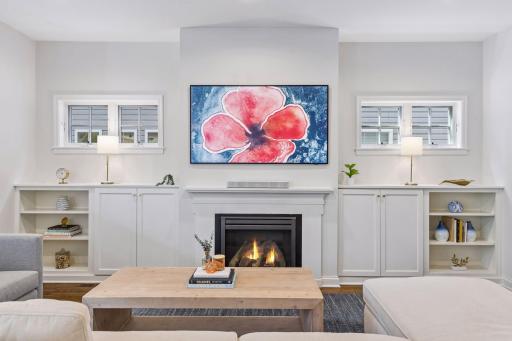 Gas fireplace surrounded by custom built-ins, and windows for natural light.