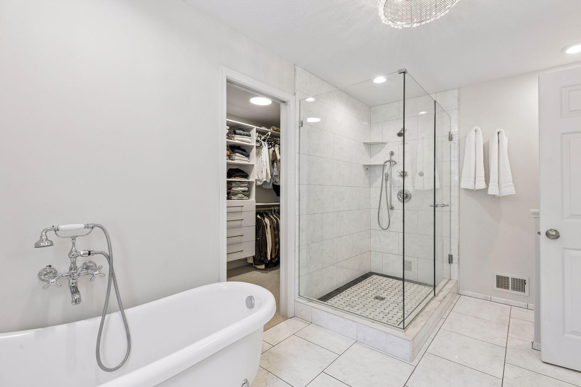 Freestanding clawfoot tub and separate step-in shower with glass wall.