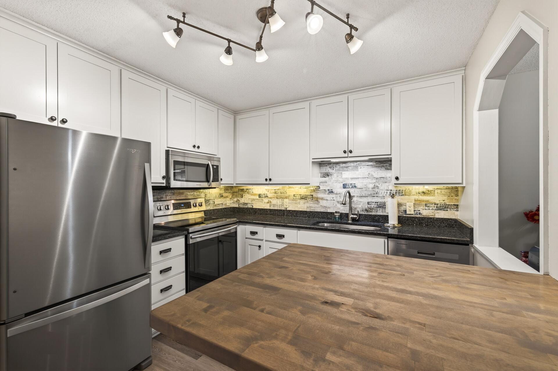 Butcher block Pennisula with stainless appliances.