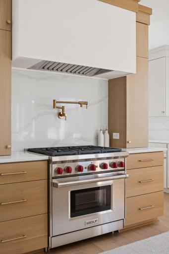 White plaster hood, pot filler, quarts backsplash and Wolf range