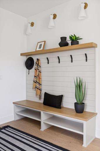 Mudroom with built in bench, storage space, and numerous hooks