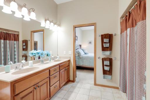 Primary walk-through bath features a long vanity with dual sinks and stand-up tile shower.