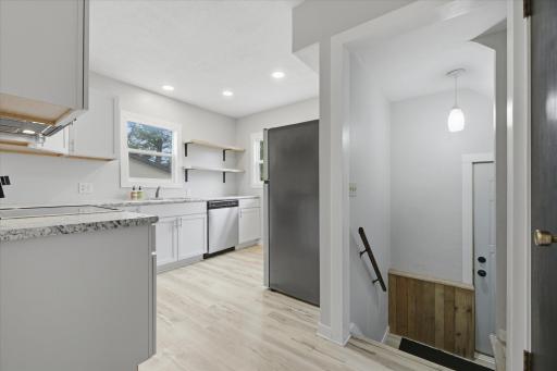 The side door entrance opens to the modern kitchen with newer cabinets, counters, & LVP flooring.