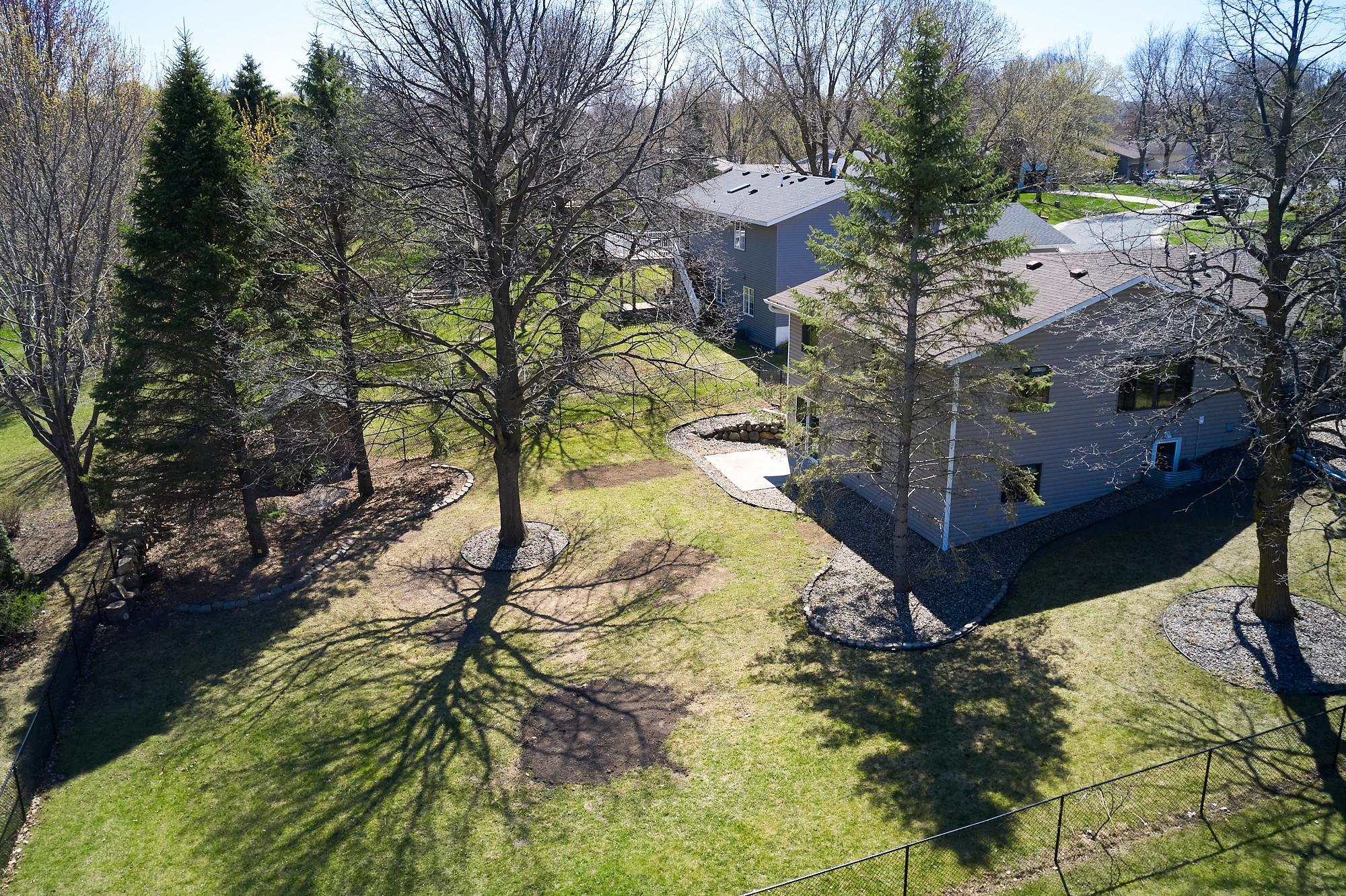 Fully fenced yard includes fruit trees and a corner of pine trees perfectly spaced to support a hammock.