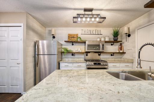 Granite counter tops & breakfast bar, industrial pipe shelving, sconce lighting, deep stainless sink, and a LG gas range.