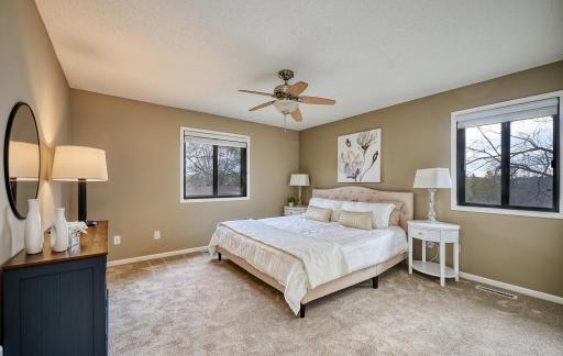 Primary bedroom has two windows with tree-top views
