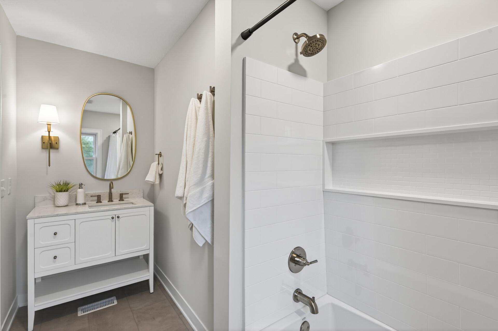 Fully updated, shared bathroom with a tiled tub/shower, vanity, and tile flooring.
