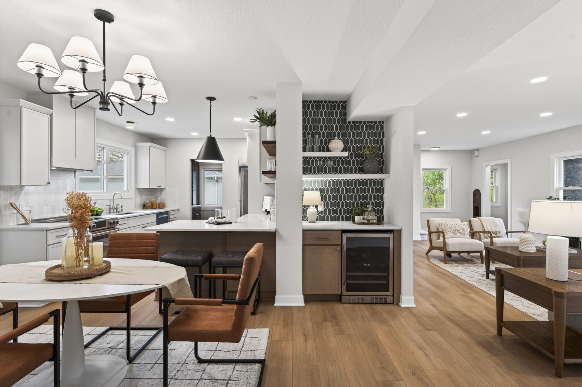 A dedicated beverage center complete with a fridge, tile backsplash, and floating shelves adds a refined yet inviting touch for effortless entertaining.