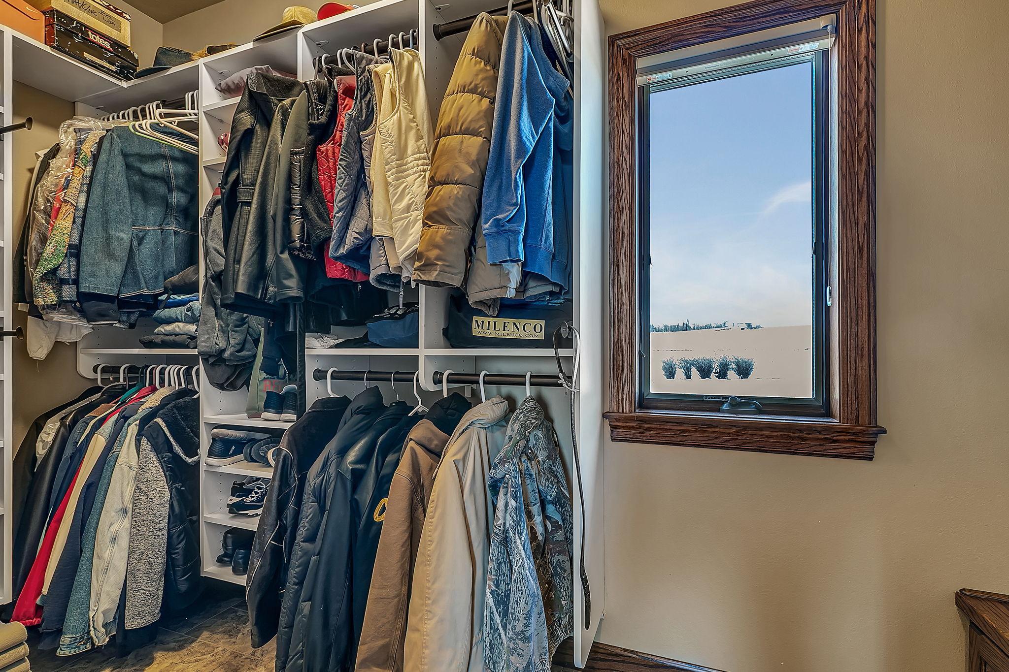 Mudroom walk-in closet off the garage entrance with natural light and built-in bench