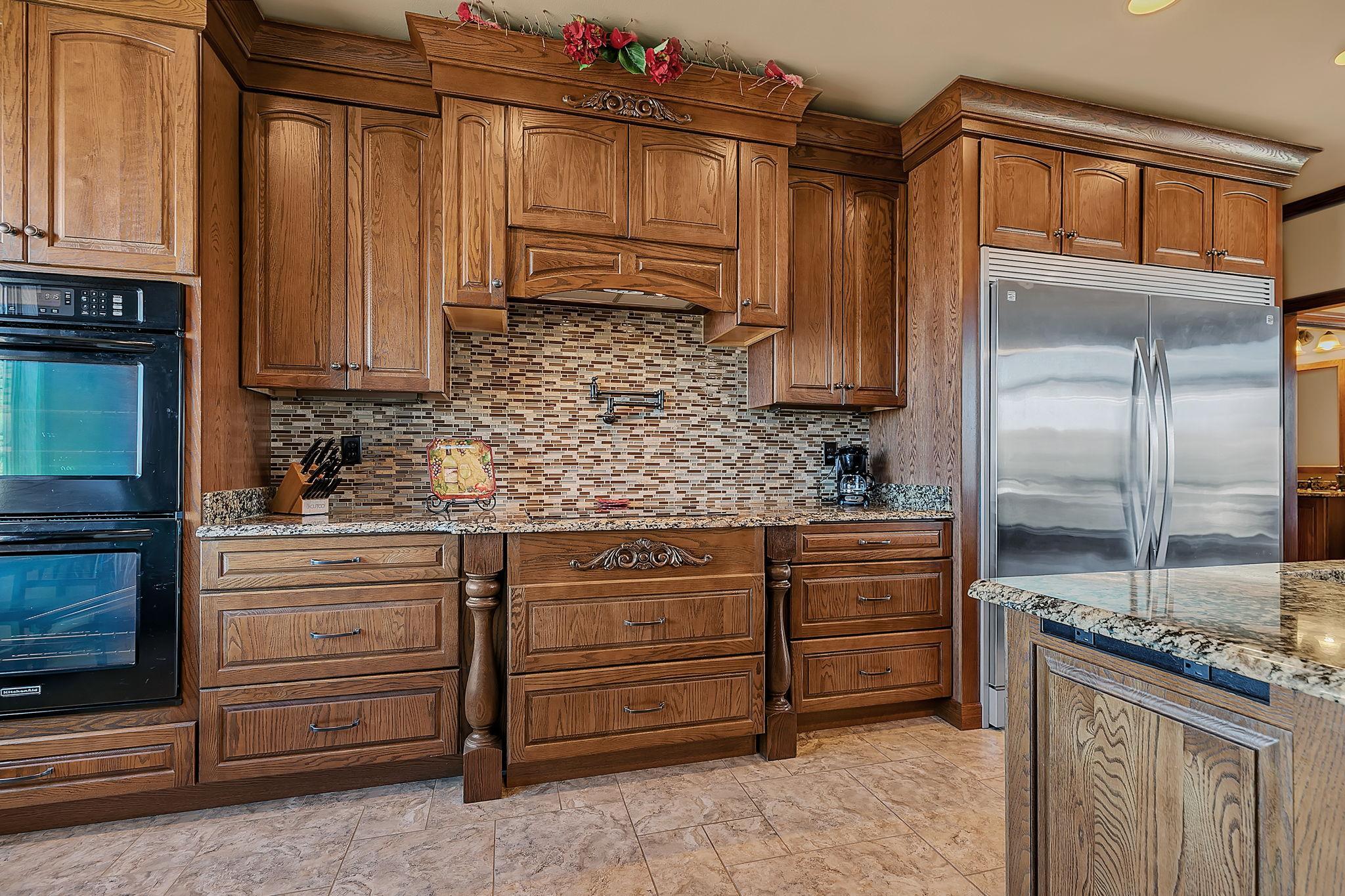 Beautiful kitchen with tile backsplash w/ pot filler, granite countertops, double refrigerator/freezer, built-in double ovens make this a dream kitchen!