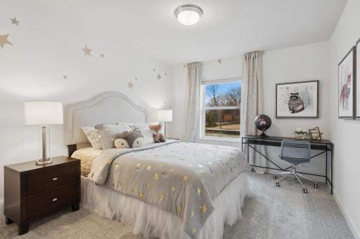 (Photo of decorated model, actual home's finishes vary) One of two generously sized upper level secondary bedrooms with spacious closets.