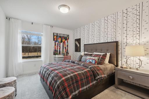 (Photo of decorated model, actual home's finishes vary) One of two generously sized upper level secondary bedrooms with spacious closets.