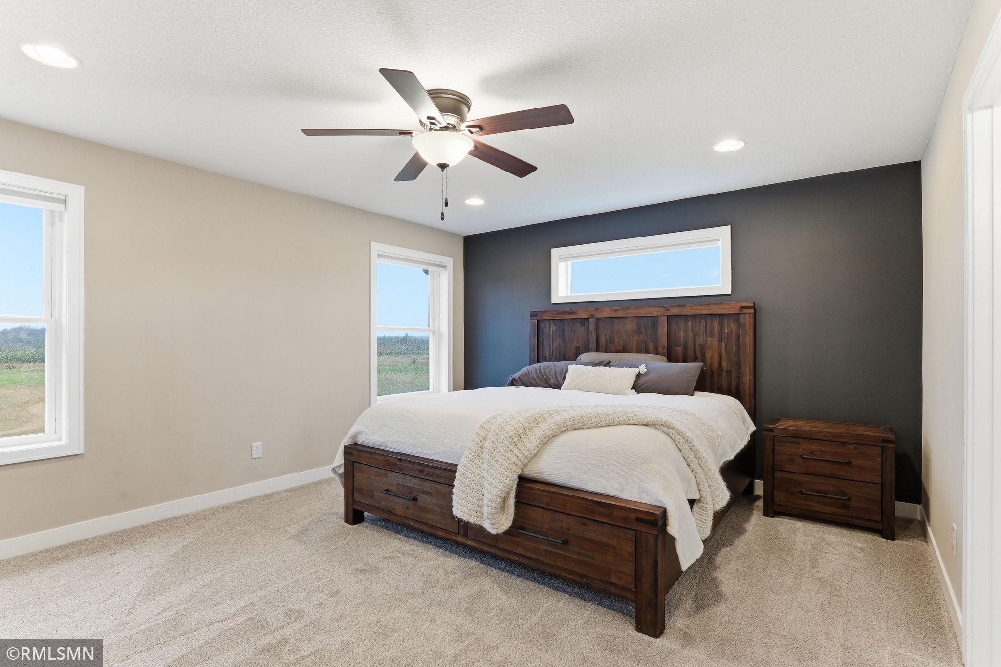 Unwind in the spacious primary bedroom featuring plush carpet, large windows, and peaceful views of the surrounding acreage. Enjoy a calm and comfortable retreat with plenty of natural light.