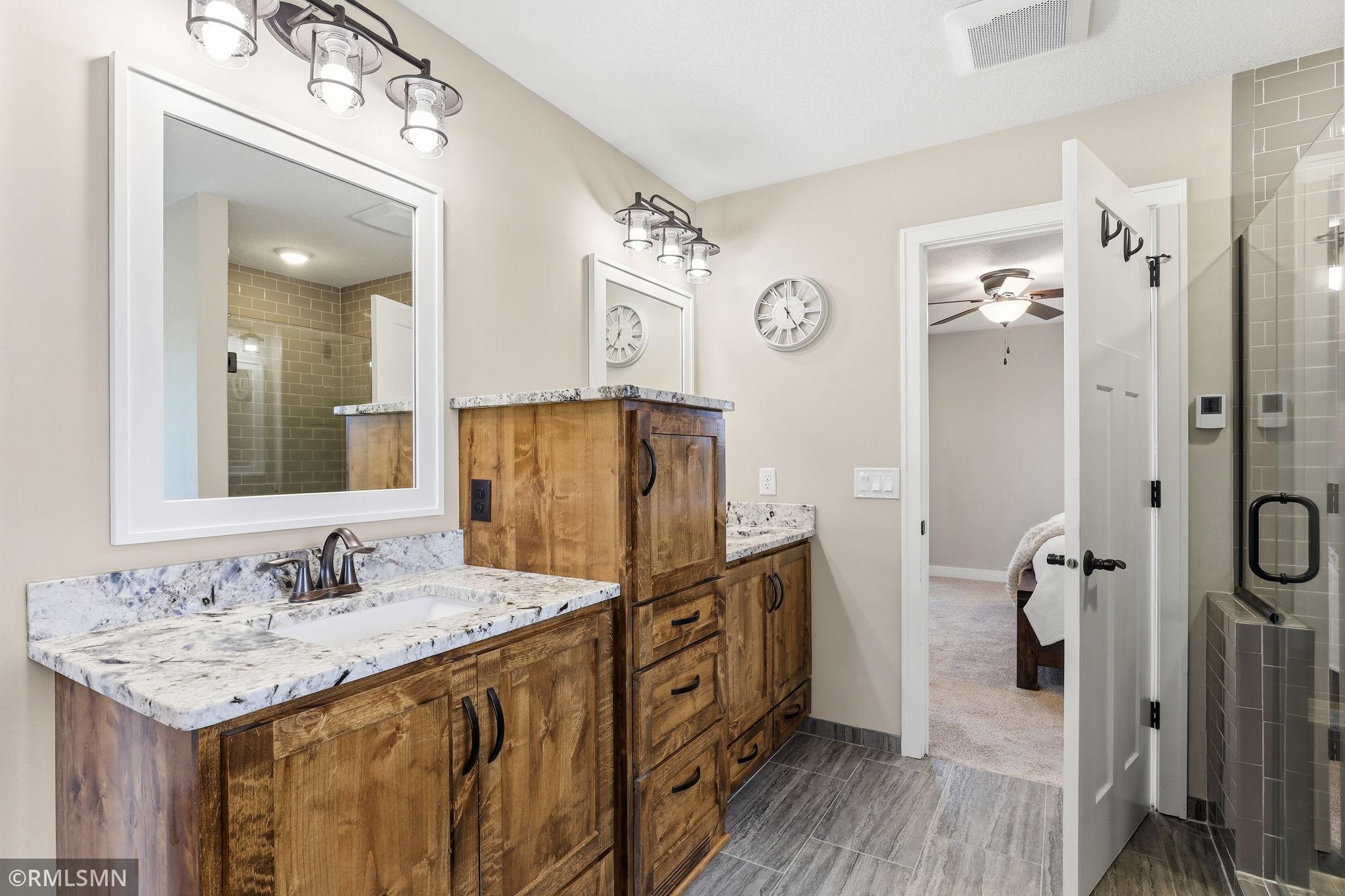 Spread out and get ready without feeling rushed in this thoughtfully designed bathroom with separate vanities and ample storage.
