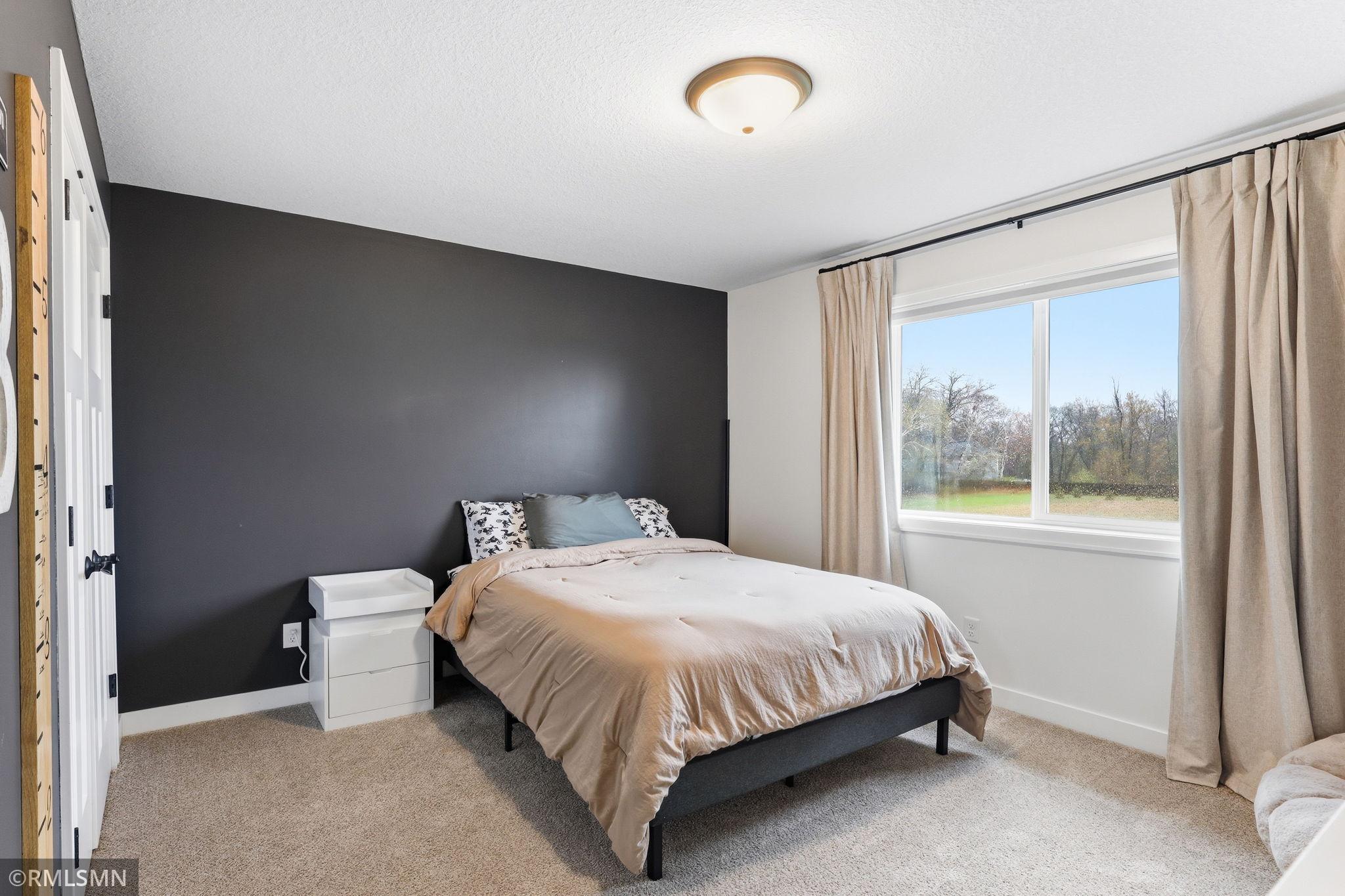 Settle in and relax in this comfortable upper bedroom with soft carpet and natural light. Unwind, recharge, and enjoy a cozy space to call your own.