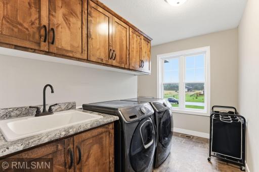 Take advantage of a bright, functional laundry room with ample cabinetry and a utility sink. Stay organized, streamline daily chores, and enjoy natural light pouring in from the large window.
