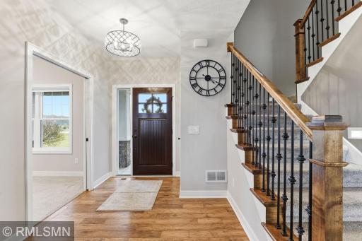 Bright and welcoming foyer featuring hardwood floors, stylish lighting, and a beautifully crafted staircase. A warm first impression with easy access to a main floor office or flex space.