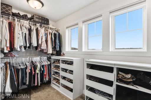Organize with ease in this spacious walk-in closet featuring custom shelving, drawers, and abundant hanging space. Sort, store, and enjoy natural light from the windows as you get ready each day.