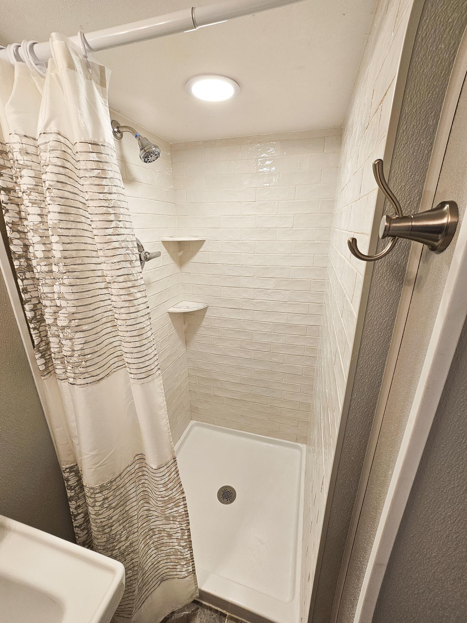 Lower level tile shower boasts classic subway tile