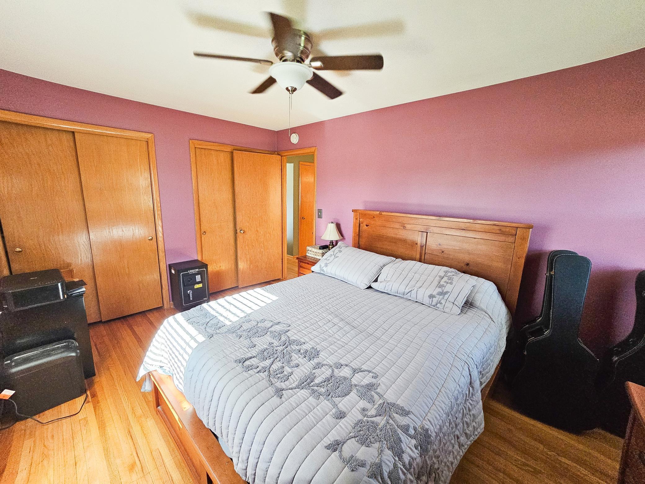 The primary bedroom features hardwood flooring, ceiling fan and an abundance of closet space.