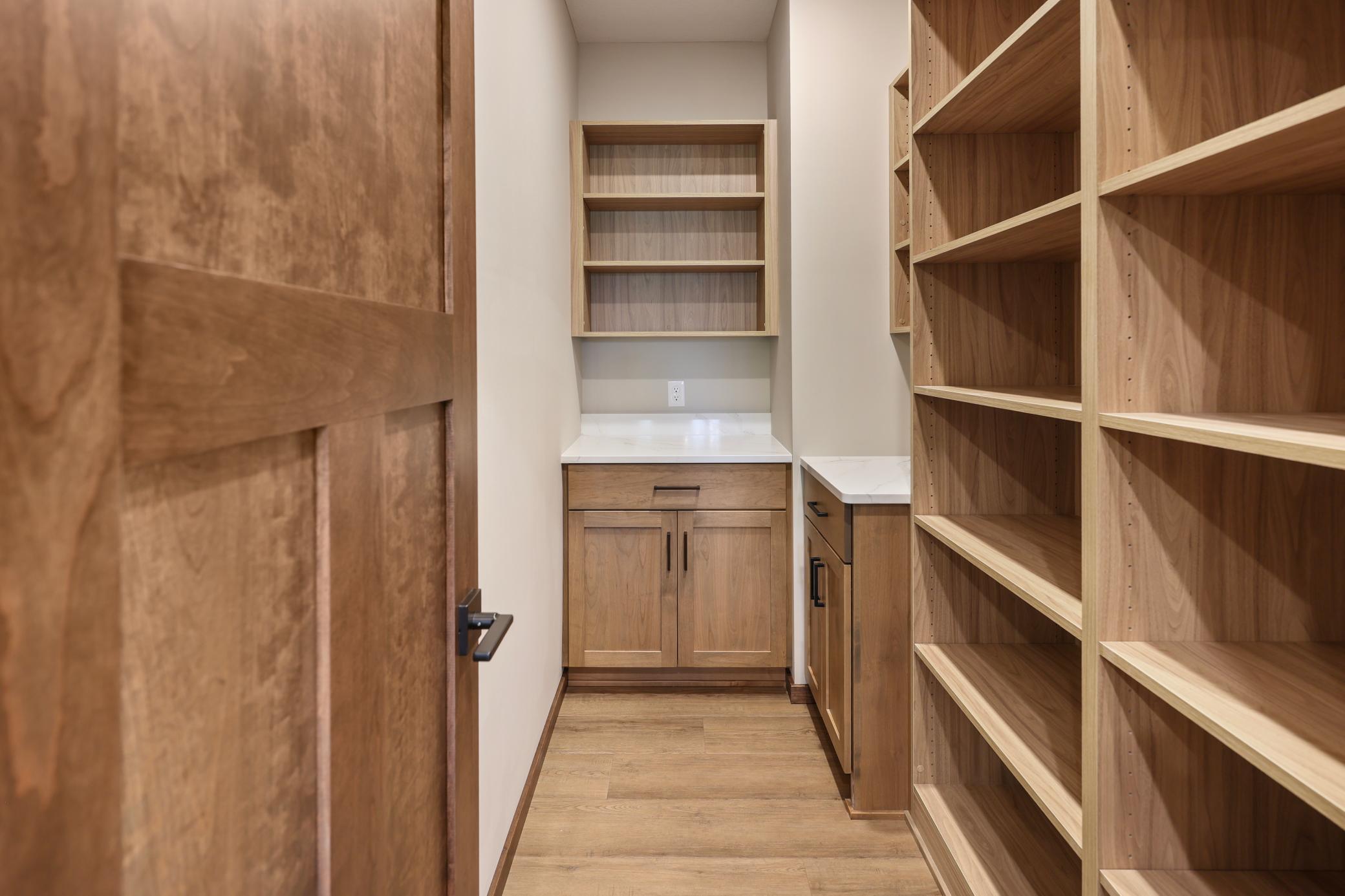 Walk in pantry offers bonus stations with quartz tops and custom shelving