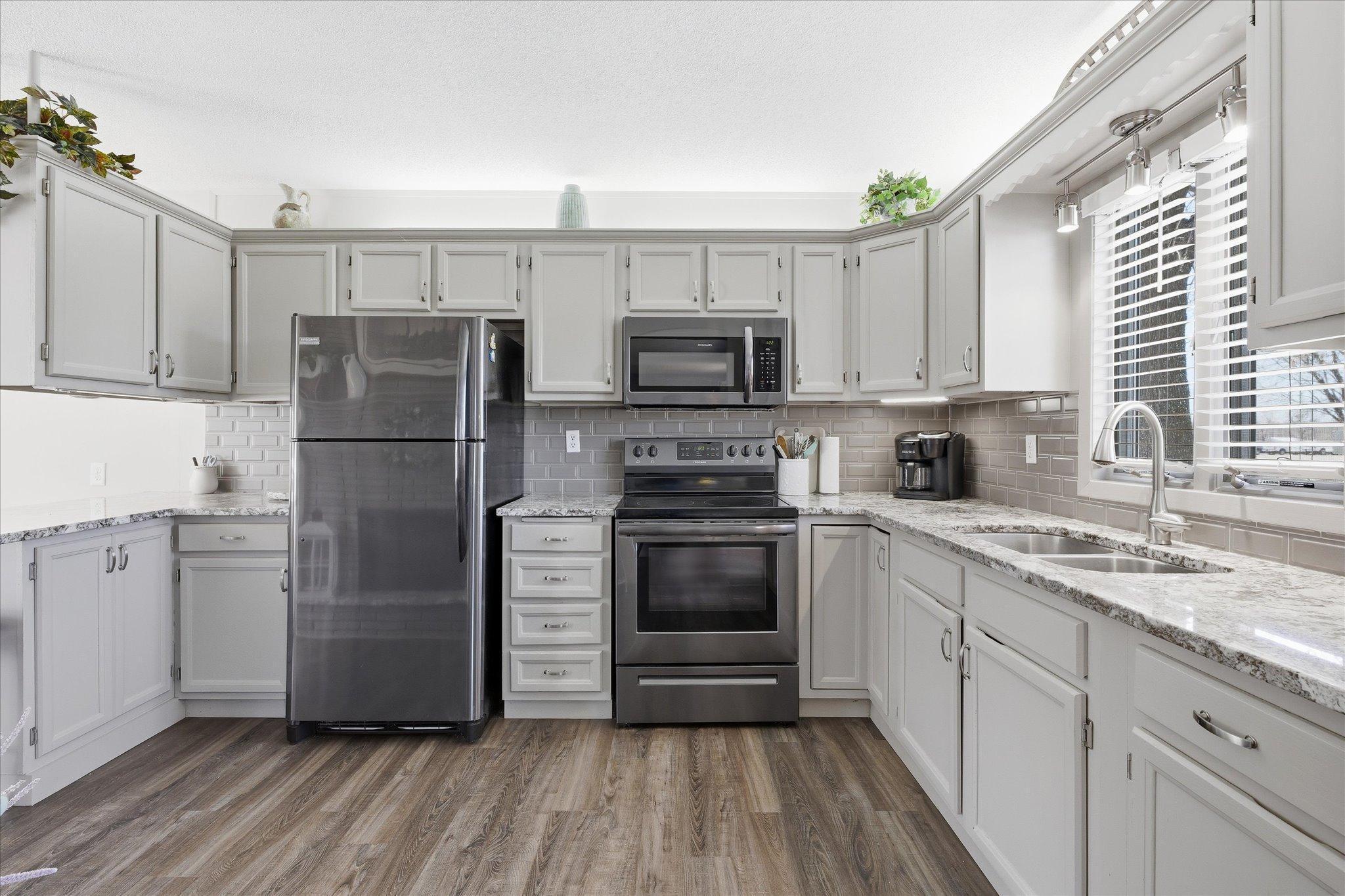 The kitchen has been remodeled with new flooring, countertops, backsplash, painted cabinets and stainless steel appliances.