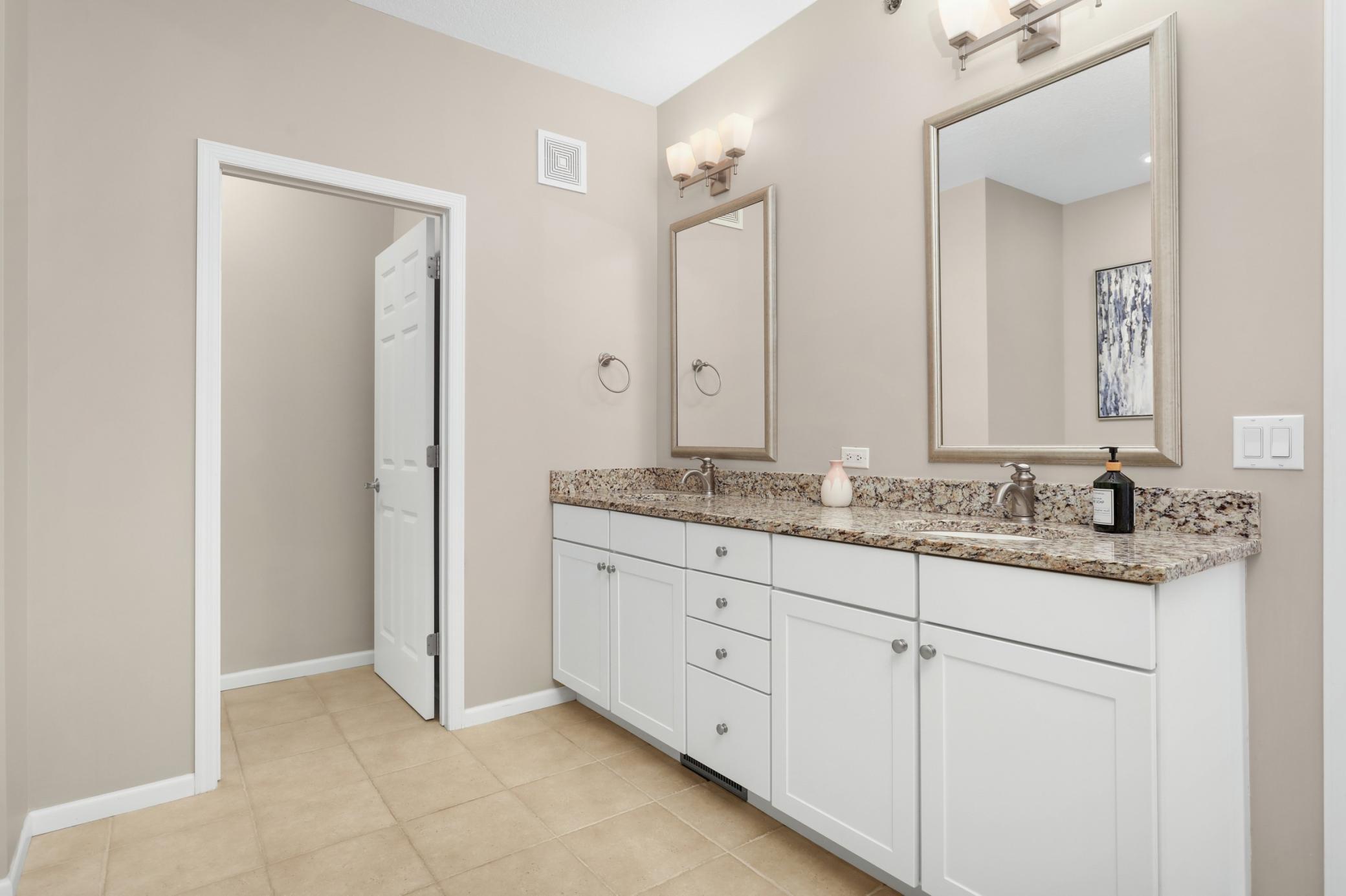 Double vanity with granite countertops and tile flooring.