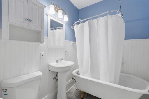 The full main level bathroom features a classic clawfoot bathtub and some extra storage behind the door.