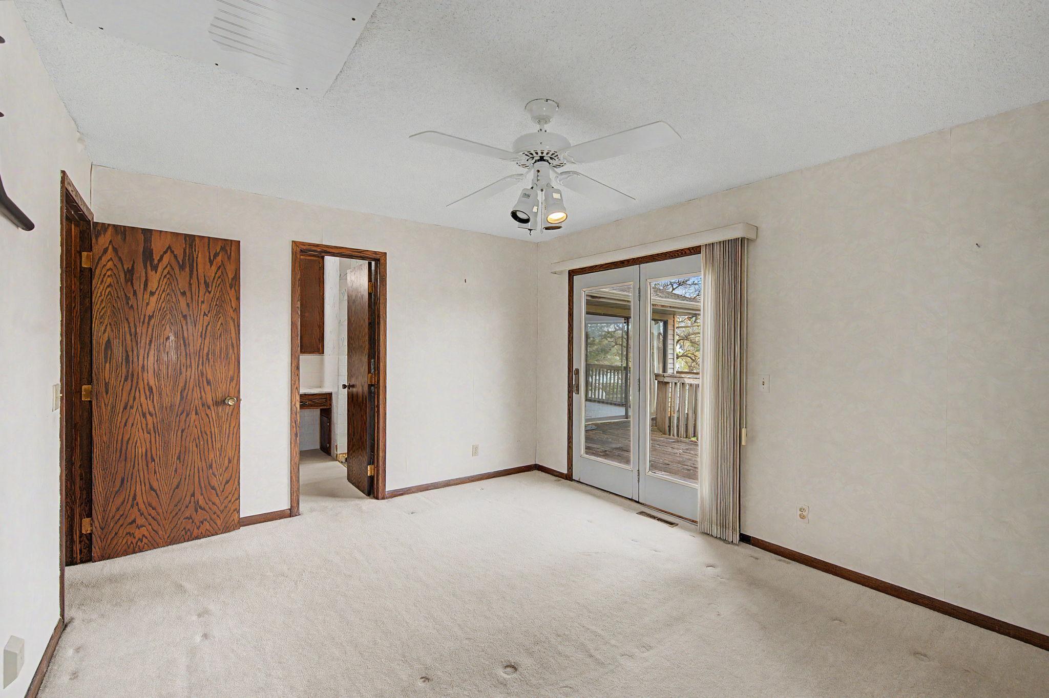 Primary bedroom with access through the French Doors to the backyard deck and there is also a walk through to the full bathroom.