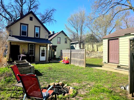 A stone firepit, back porch, and raised garden beds can be found in the backyard