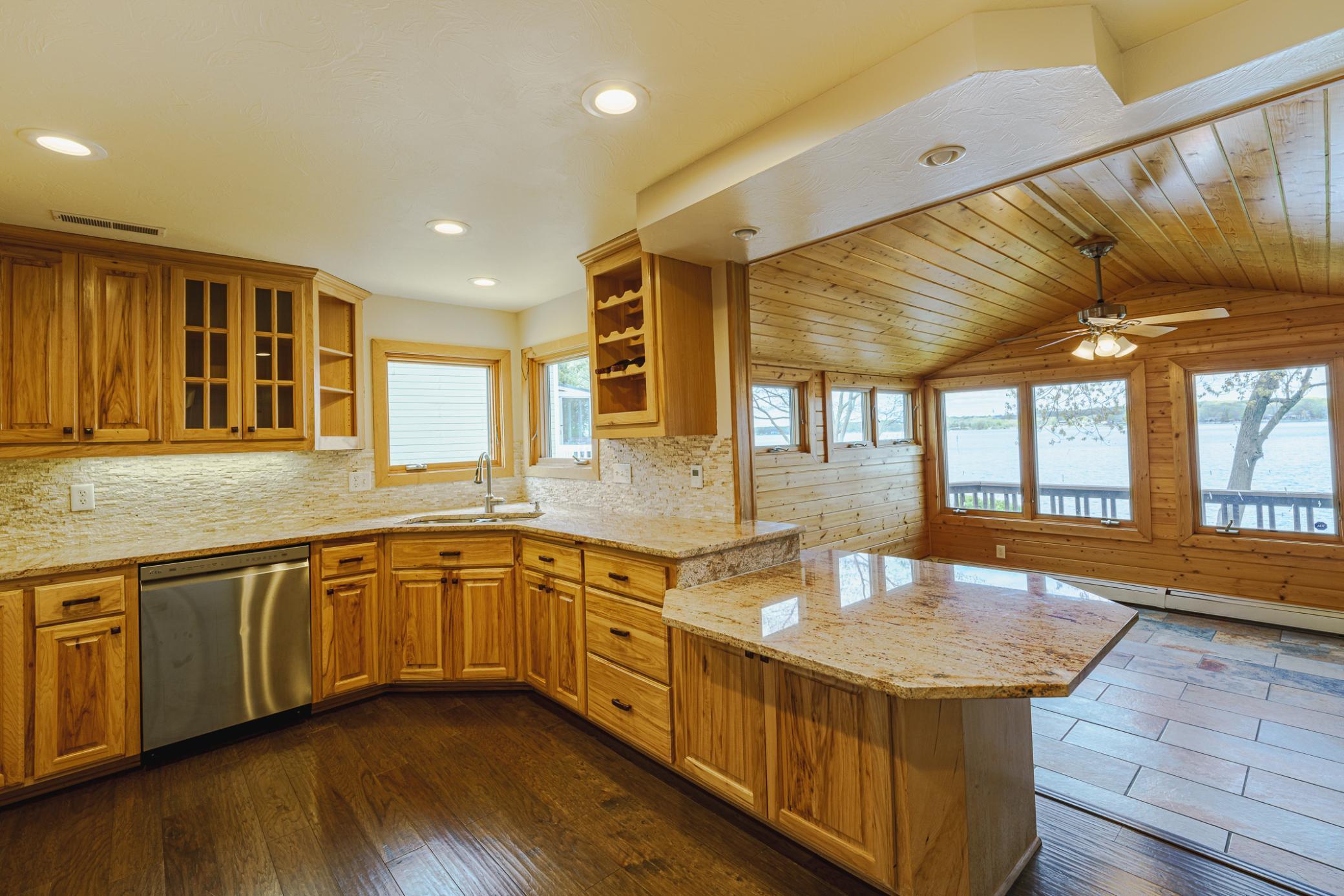 The kitchen has updated cabinetry, wood-style flooring, granite surfaces and stainless appliances. Lake views can be enjoyed from corner kitchen windows and the sunroom.