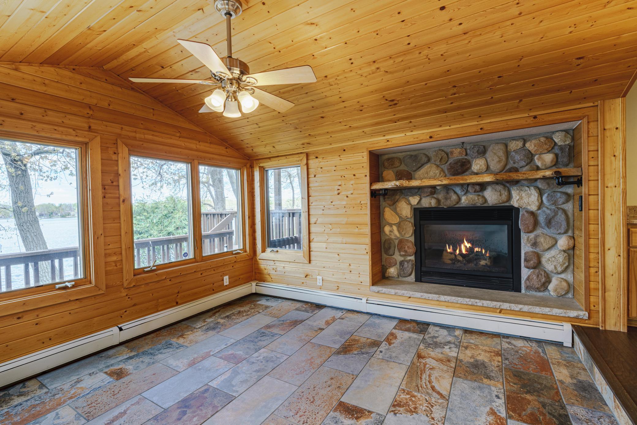 The four season porch/sunroom has a vaulted ceiling with a fan, and a stone/gas fireplace. Open the windows and let the lake breeze in.