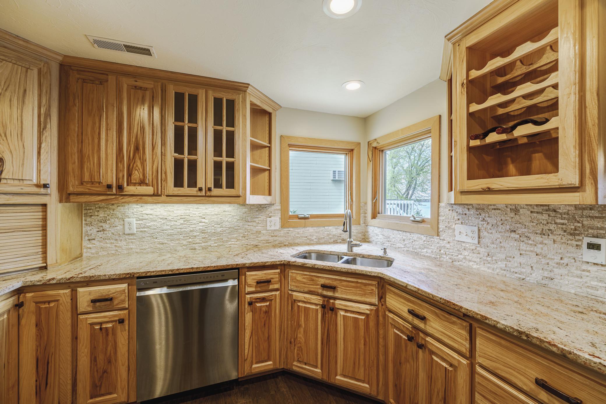 The kitchen has operable corner windows, under cabinet lighting, granite surfaces and a dry-stack backsplash. The cabinetry has both solid and gridded glass doors, and space for wine storage.