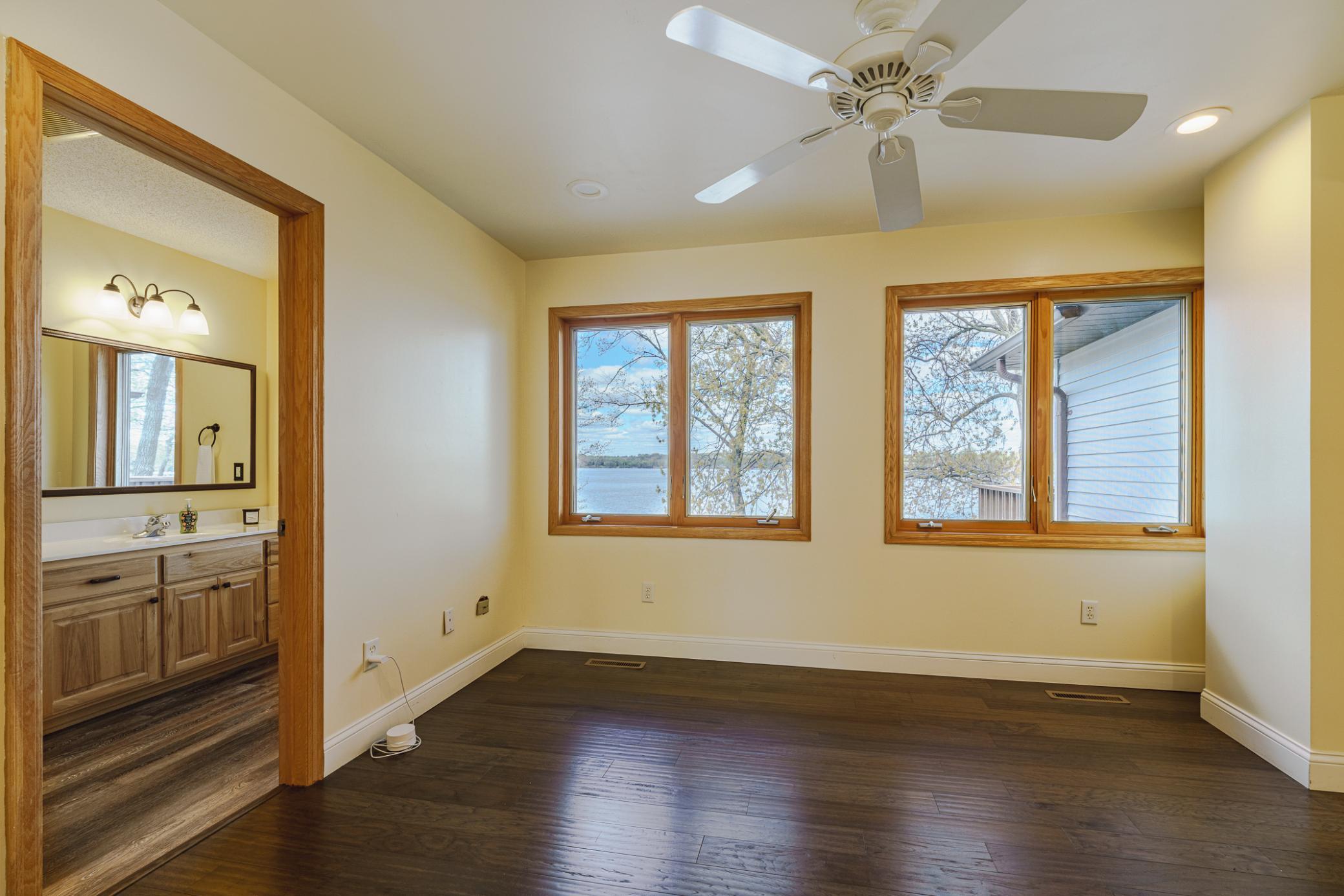 The loft has rich flooring, white trim and a ceiling fan.