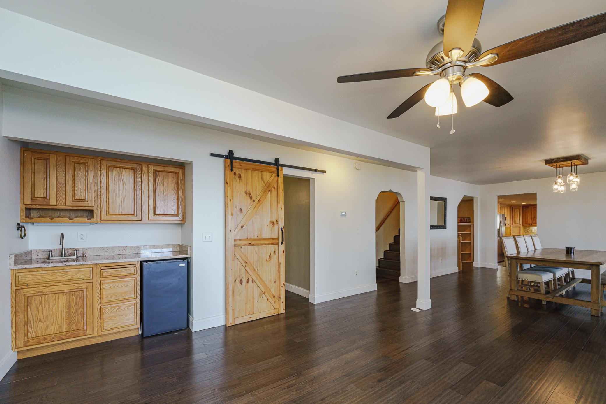 When in the living room, the layout (from left to right) starts with the serving bar, then the sliding barn door to the main floor bedroom/office. The arched doorway leads to the staircase to the upper level, then the foyer entry and kitchen entry.