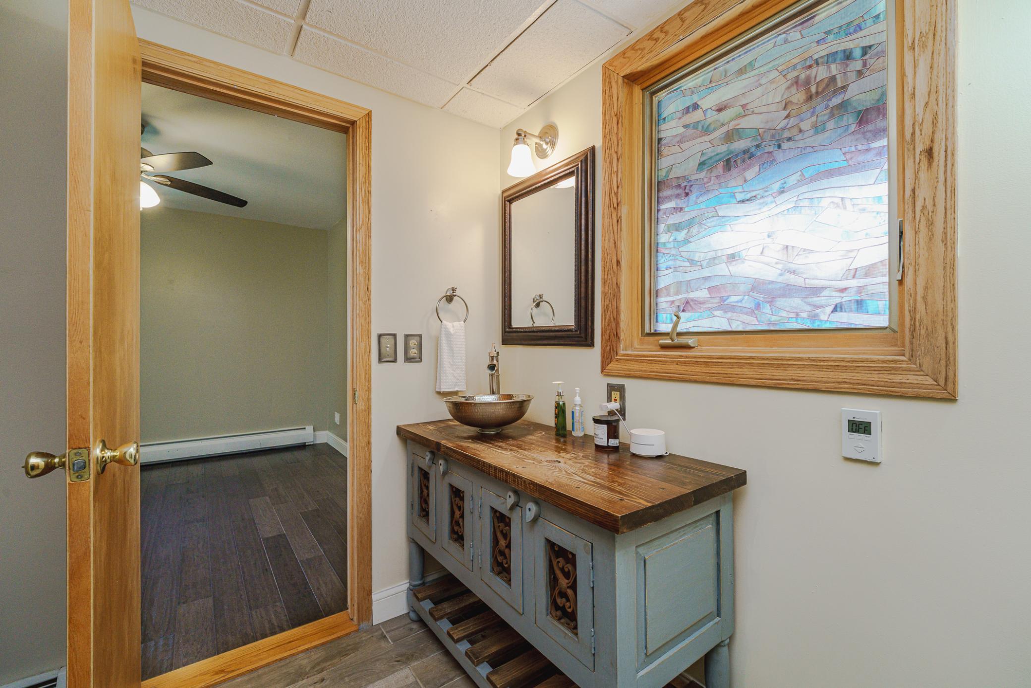 This 3/4 bathroom has been updated with a beautiful furniture-style vanity and a stained glass concealed window.