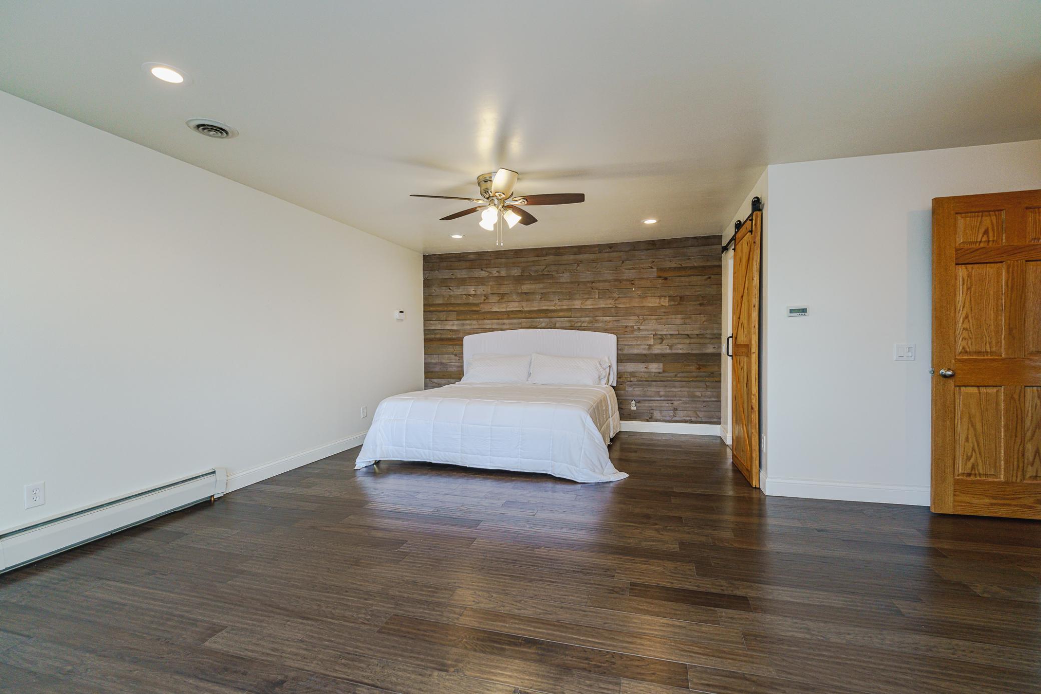 The primary suite is ENOURMOUS and has shiplap details, a ceiling fan, solid pane doors including a sliding barn door to the bathroom, and a patio slider to the deck.