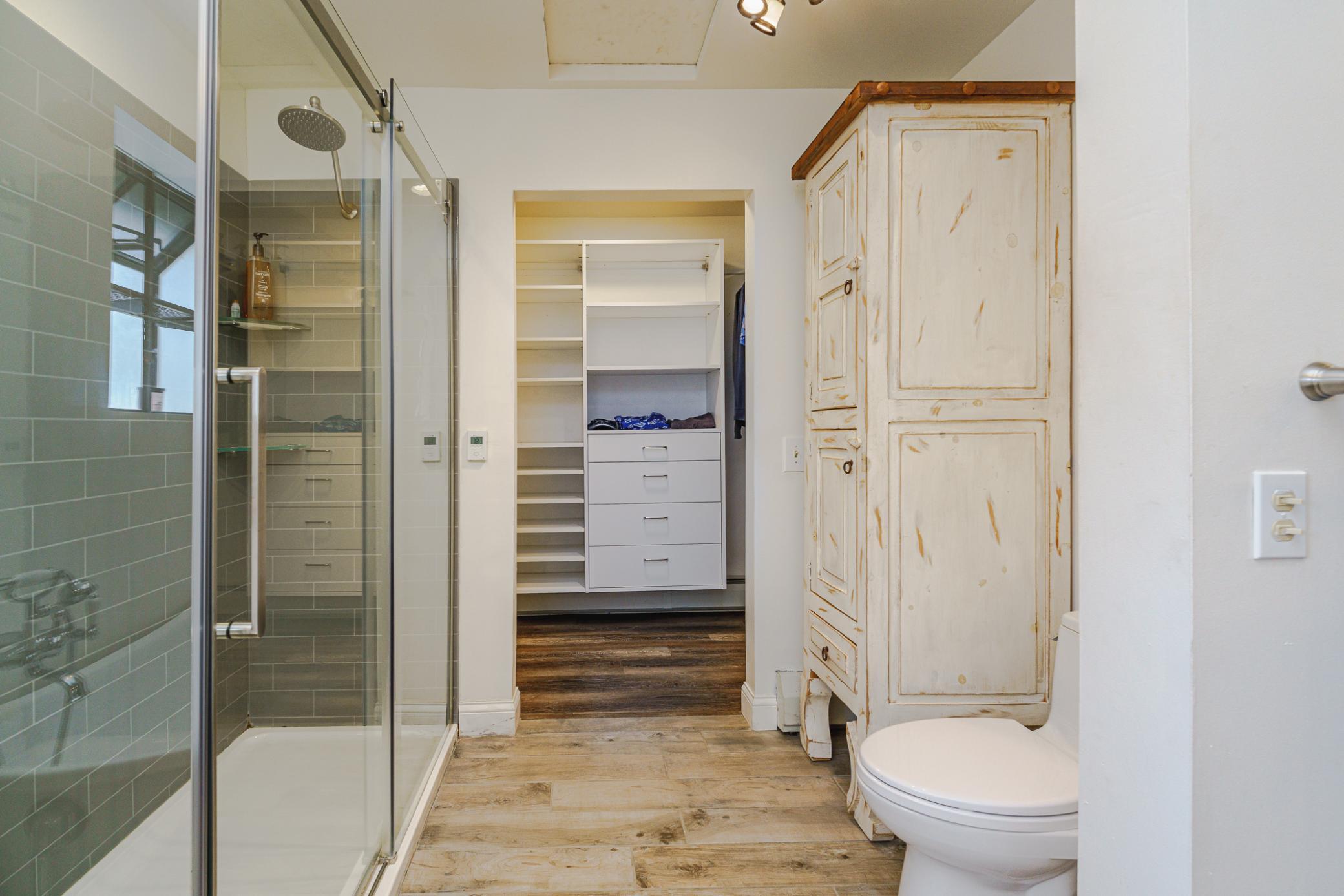 The primary bath has TWO walk-in closets. One is just beyond the linen stack.