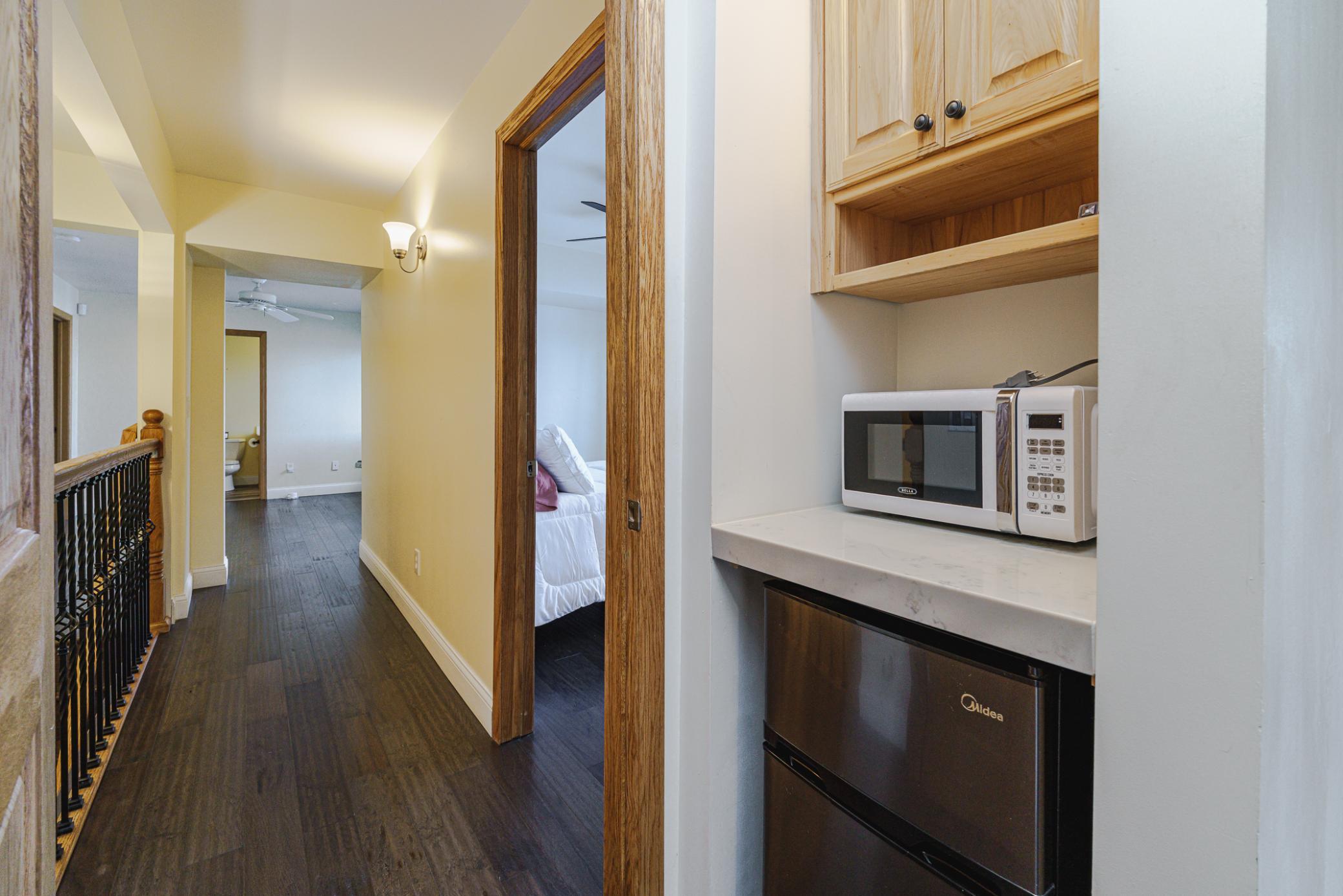 Entrance to the two bedrooms at the far end of the upper hall. The primary suite has a serving bar. Updated iron balusters line the stairwell.