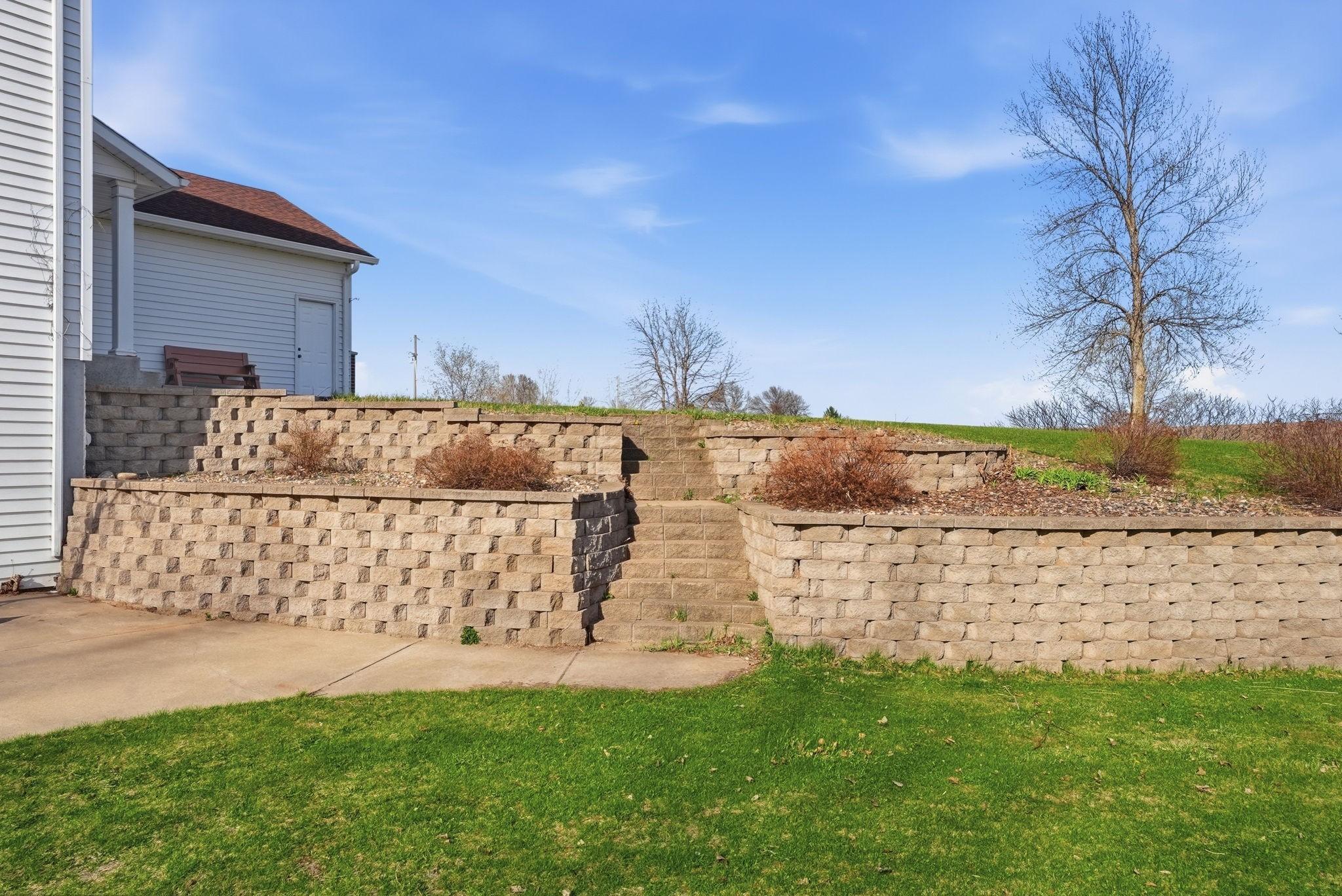 Beautiful landscape with retaining walls and stairs leading to patio area