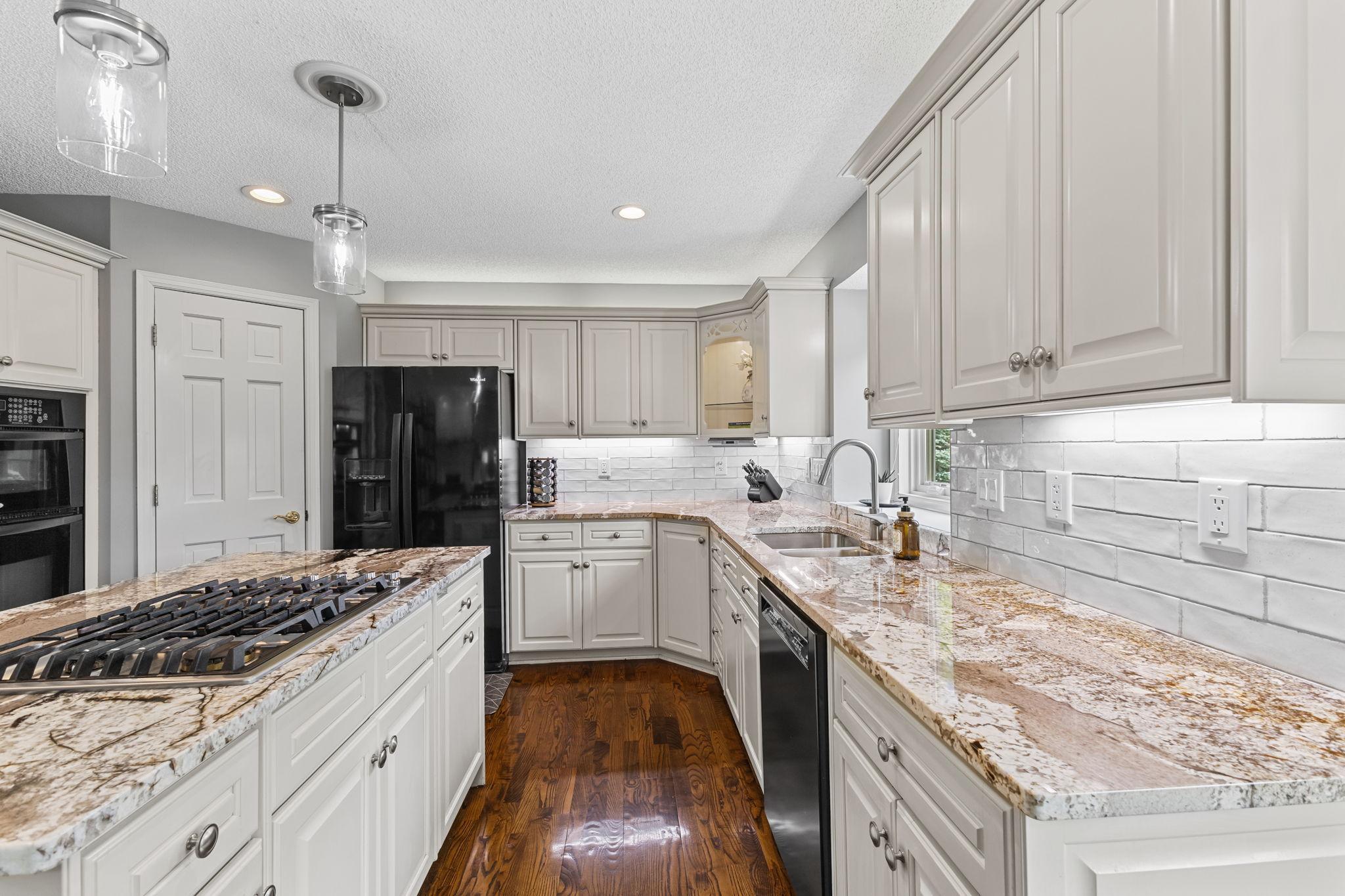 The custom tile backsplash, under & above cabinet lighting plus interior accent cabinet lighting provide thoughtful design details that make this a standout kitchen.