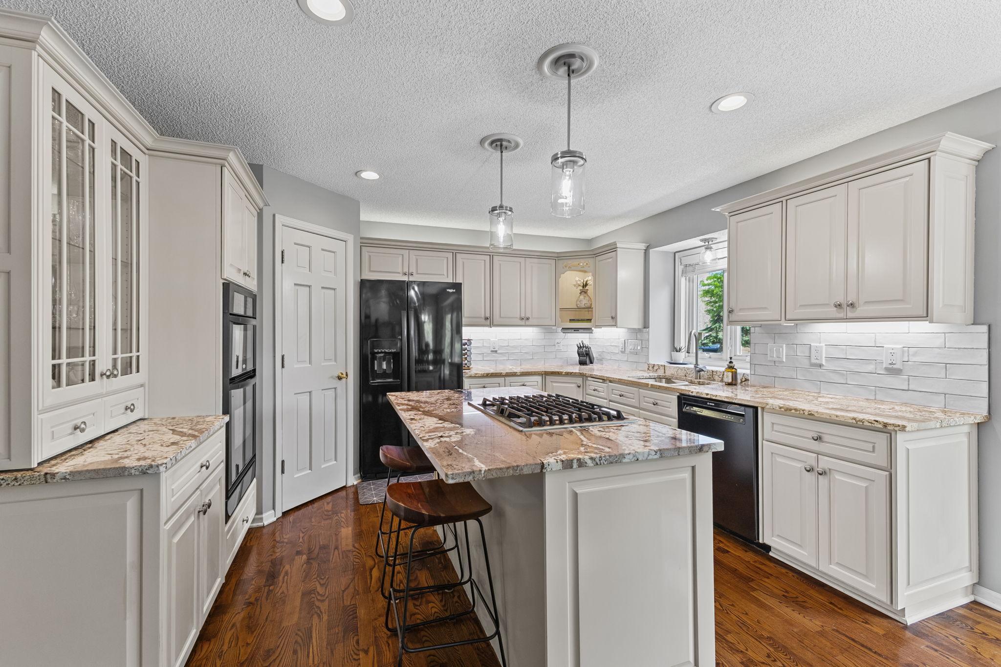The beautiful white enamel cabinetry is framed with a warm rich finish on the natural hardwood floors. The 2019 kitchen remodel features new granite, pendant lighting, range & dishwasher.