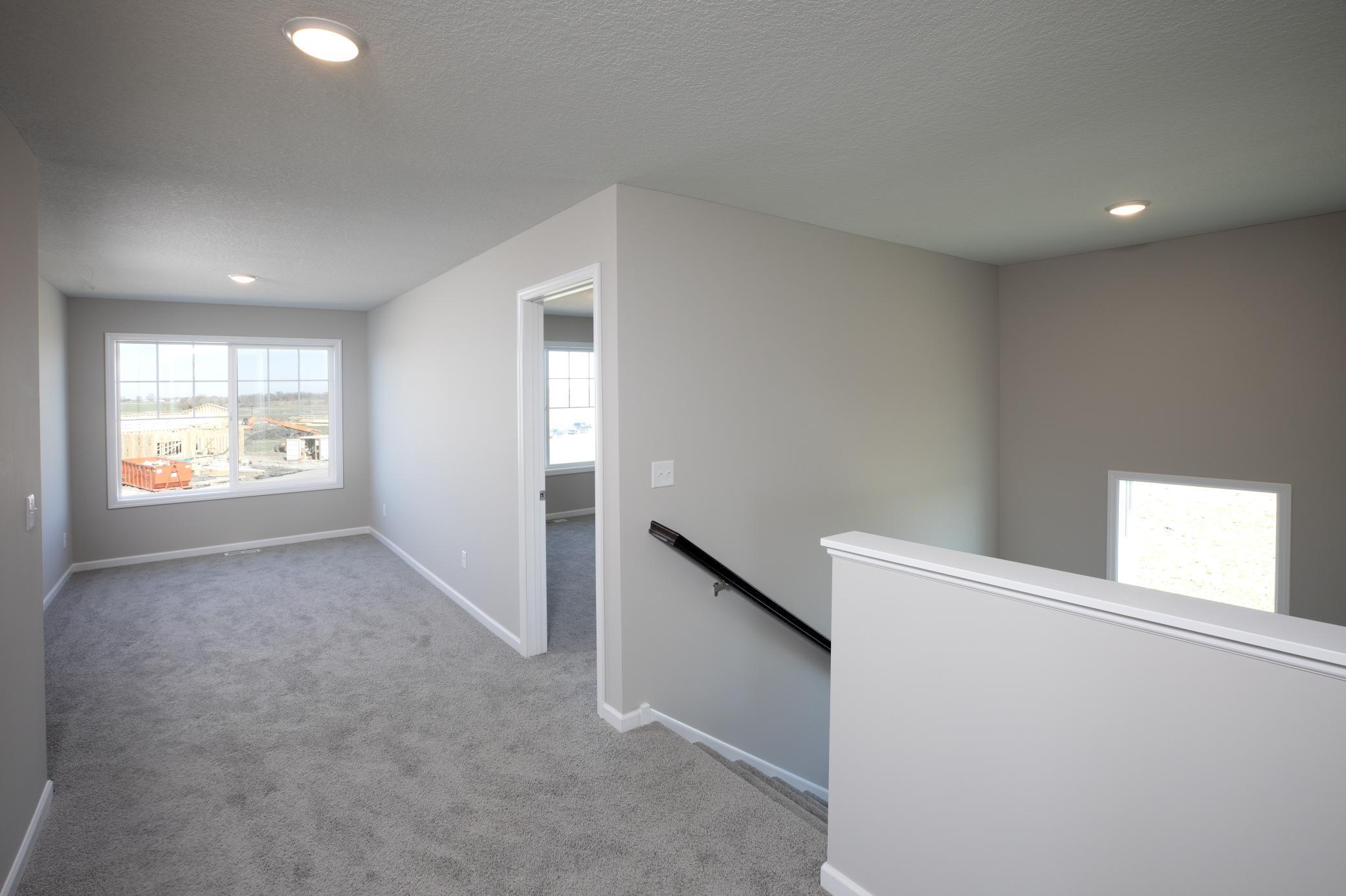 PHOTO OF A DIFFERENT HOME WITH SIMILAR PLAN. FINISHES MAY VARY. Upper Level Hallway View to Staircase and Versatile Loft area.