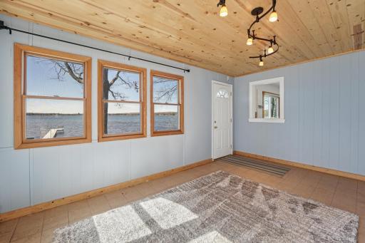 Corner sunroom with lots of windows, charming knotty pine ceiling, and a pass-through window to the kitchen. Natural light and effortless entertaining all in one space.
