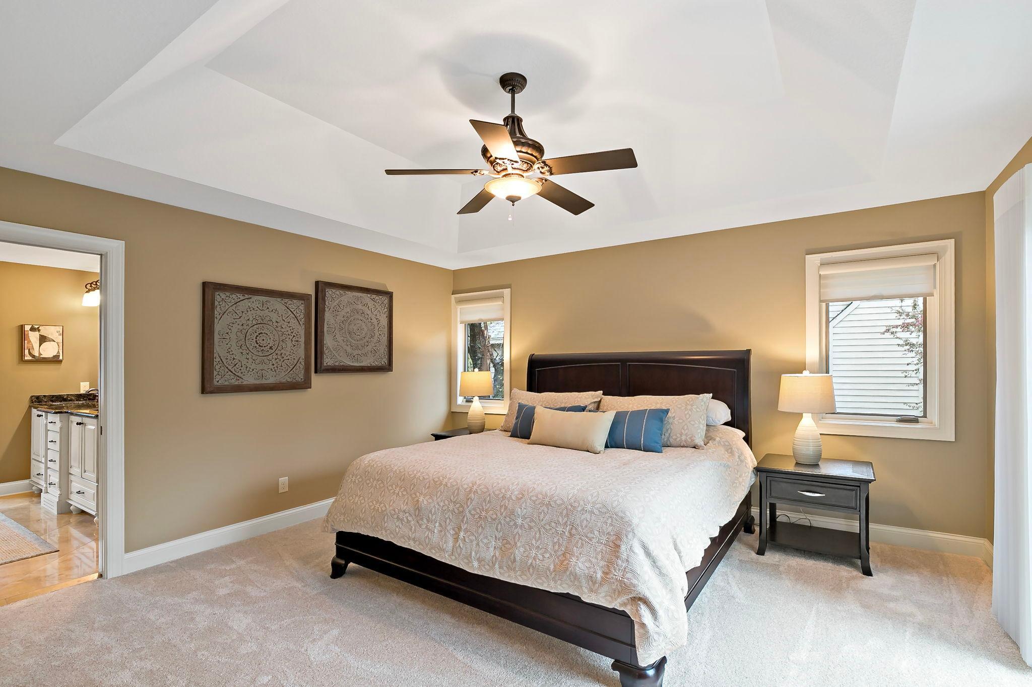 Retreat to this lovely main-floor primary suite with tray ceiling and private deck overlooking the pond.
