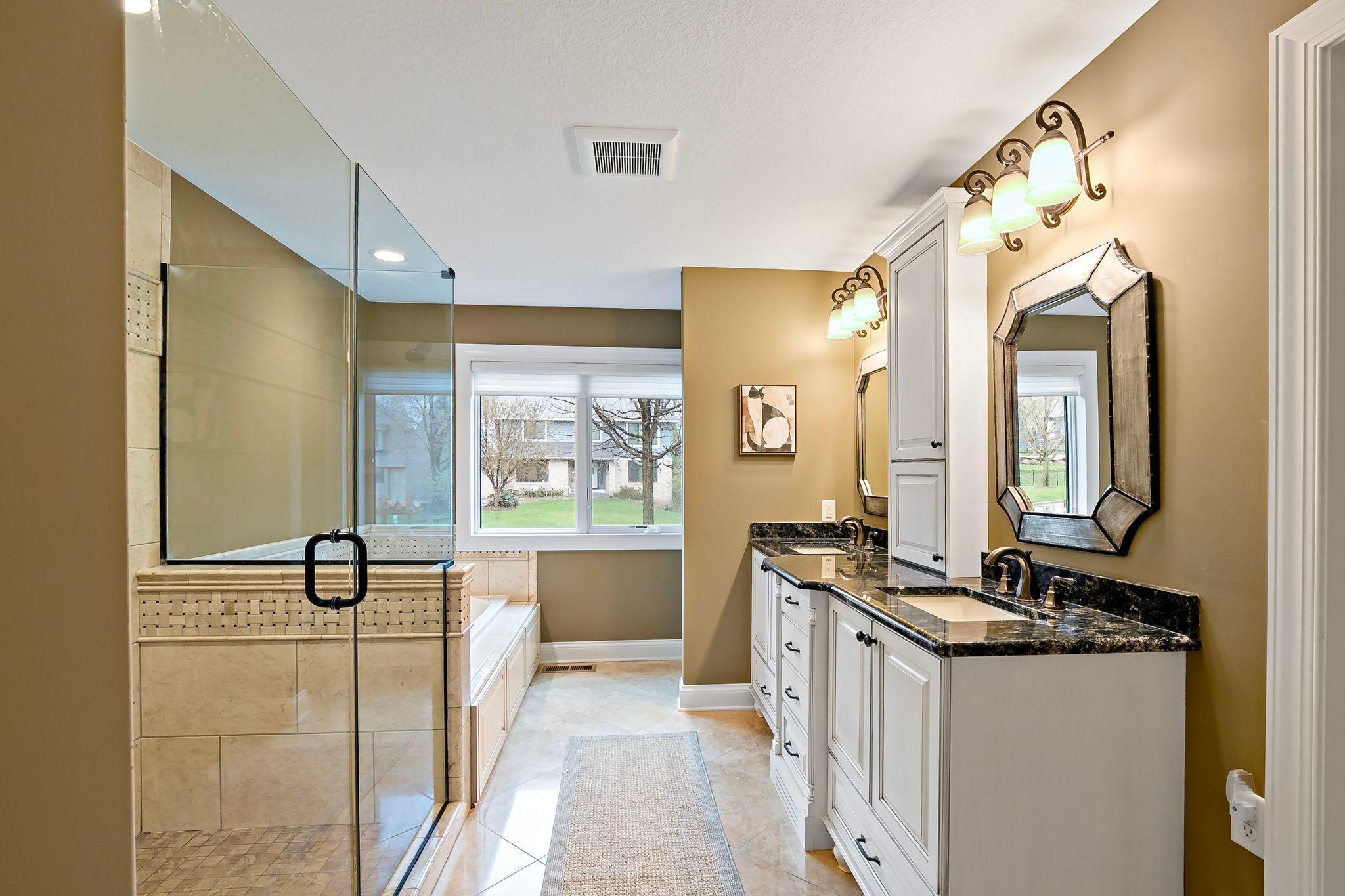 Absolutely fabulous primary bath renovation with dual sink, soaking tub, and glass shower with custom tilework.